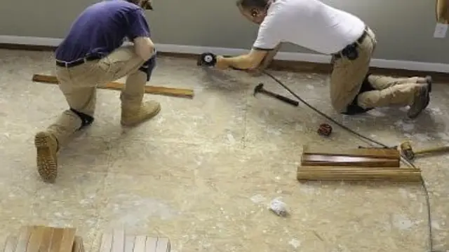 Two workers installing new flooring after water damage